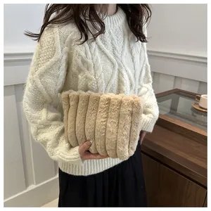 Detail einer beigen Webpelz-Clutch mit vertikaler Streifenstruktur in der Hand