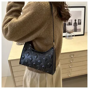 Detailed close-up of black textured underarm bag with fan-pattern embossing on the leather
