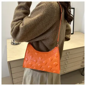 Detail of orange crescent underarm bag with unique fan-shaped quilted texture