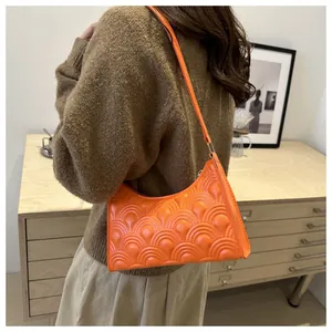 Close-up of bright orange underarm bag featuring embossed wavy texture and PU leather