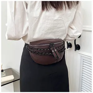 Gros plan d'un sac ceinture marron texture crocodile avec chaînes noires sur modèle