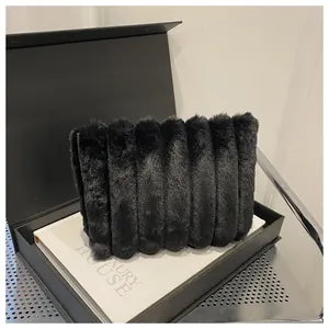 Nahaufnahme der schwarzen Kunstfell-Clutch mit weicher Textur in einer Geschenkbox
