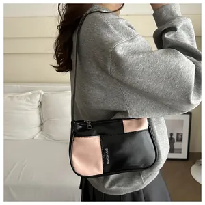 Detail of minimalist underarm bag with black and pink patchwork design and silver zipper