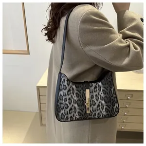 Détail du sac léopard gris avec fermoir doré porté sur un manteau beige