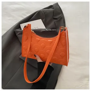 Detail of orange underarm bag showing half-circle wave embossed texture and gold metal ring