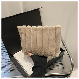 Detail einer beigen Webpelz-Clutch mit modischer Rippenstruktur und weichem Plüschmaterial
