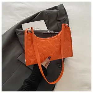 Macro detail of bright orange underarm bag featuring unique scale-like embossed texture