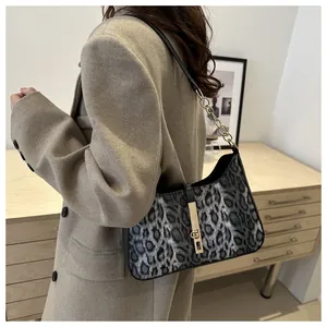 Détail du sac léopard sous le bras avec chaîne dorée et boucle à piston en métal chic