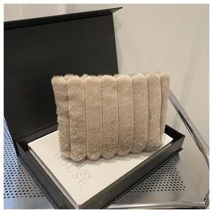 Detailansicht einer beigen Kunstpelz-Clutch mit vertikaler Steppung in einer Box
