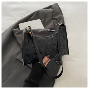 Detail of black quilted underarm bag with wavy texture on a grey blazer background