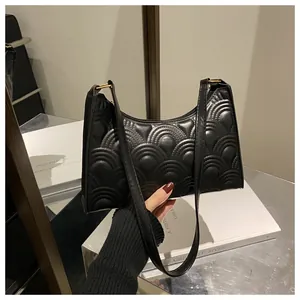 Detailed view of black underarm bag featuring fan-shaped quilting and gold hardware
