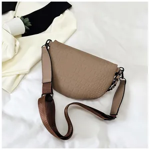 Détail du sac selle kaki à motif crocodile avec large bandoulière en tissu tressé
