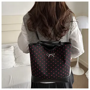 Detail view of the red heart patterns and silver bow on the black polka dot bucket bag