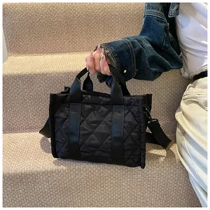 Détail du sac cabas matelassé noir montrant les coutures en losange et la bandoulière