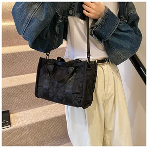 Détail du sac fourre-tout noir matelassé avec larges poignées et grand compartiment
