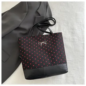 Detailed view of polka dot bucket bag with red hearts and a silver metallic bow decoration