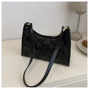 Detail of black underarm bag featuring elegant semi-circle quilted texture and gold zipper