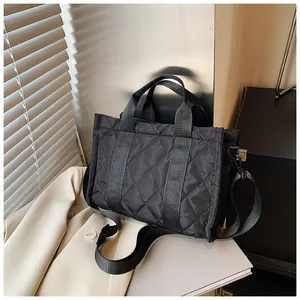 Détail du sac à main en nylon noir matelassé avec motif losanges et large bandoulière