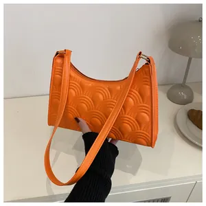 Detailed view of orange underarm bag featuring fan-shaped quilted patterns and texture