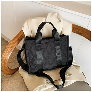 Gros plan du sac cabas en nylon matelassé noir avec coutures en losange et doubles anses