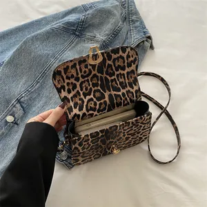 Sac carré imprimé léopard avec boucle dorée et bandoulière en cuir sur veste en jean