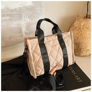Détail du sac matelassé beige montrant la texture en losanges et les anses noires