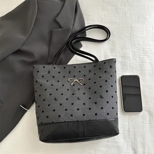 Grey polka dot bucket tote with bow embroidery and metallic clasp on white background