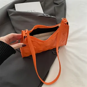 Minimalist bright orange quilted underarm shoulder bag styled on a grey blazer