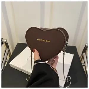 Détail d'un mini sac en forme de cœur marron foncé avec texte doré et chaîne en argent