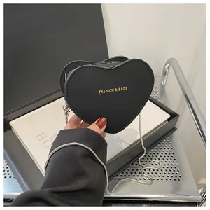 Détail du sac bandoulière en cuir en forme de cœur avec chaîne et lettrage doré