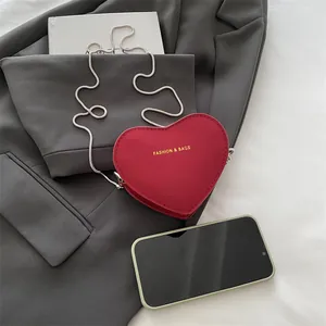 Mini sac à bandoulière rouge en forme de cœur avec chaîne sur blazer gris