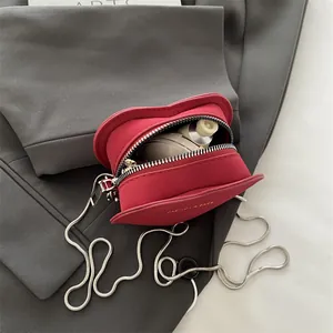 Mini sac à bandoulière rouge en forme de cœur avec chaîne présenté sur une veste grise