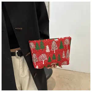 Détail d'une pochette de maquillage rouge de Noël avec motif forêt et zip en métal