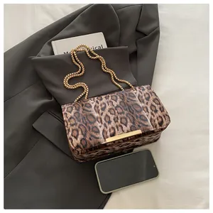 Detail of leopard print crossbody bag with golden chain and metallic trim on fabric