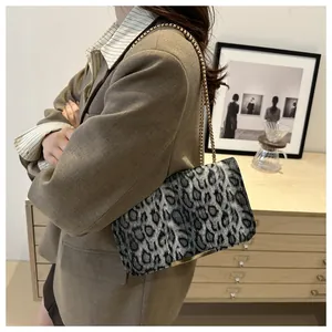 Detailed view of leopard print shoulder bag with gold chain strap on a model