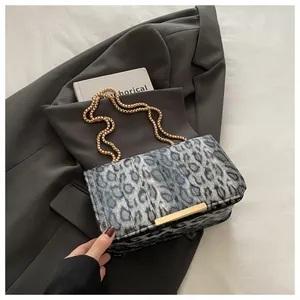 Close-up of leopard print shoulder bag with gold chain strap on grey blazer