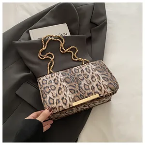 Detail of leopard print crossbody bag with gold chain strap on grey blazer