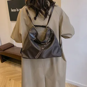 Minimalist large capacity coffee brown nylon tote bag shown on model in a soft indoor setting
