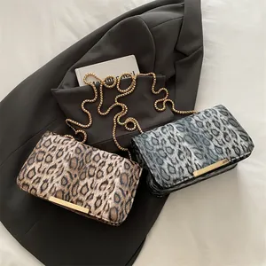 Fashionable leopard print chain crossbody bags in tan and grey tones on a suit