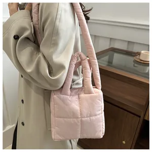 Close-up of pink quilted puffer tote bag carried by a model in a beige trench coat