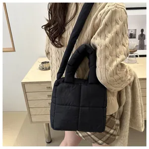 Close-up of black quilted puffer tote bag with thick handles in a cozy home setting