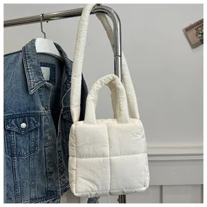 Detail of white quilted tote bag hanging on a rack showing fluffy cross-stitch texture