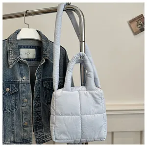 Detail of light blue quilted tote bag featuring square padding and soft shoulder strap