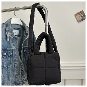 Detail of black quilted puffer tote bag with soft padded texture and crossbody strap