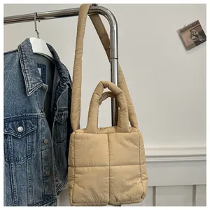 Detail of quilted puffy tote bag in beige with soft square pattern and shoulder strap