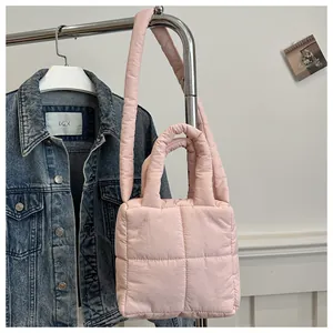 Detail of pink quilted puffer tote bag hanging with a shoulder strap and soft square texture