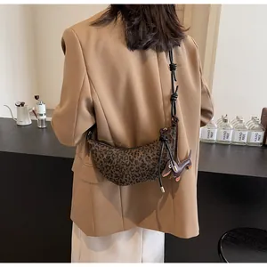 Detail der sichelförmigen Leopard-Tasche mit schwarzem Knotengurt und Dackel-Anhänger