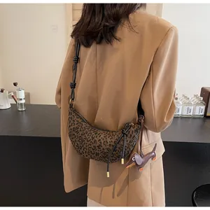 Schultertasche mit Leopardenmuster, Lederriemen und Dackel-Anhänger am Modell getragen