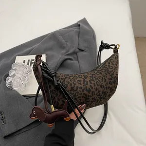 Detail der Halbmond-Tasche mit Leopardenmuster, Dackel-Anhänger und schwarzem Knotengriff