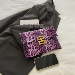 Purple leopard print envelope clutch bag with gold metal clasp on white fabric